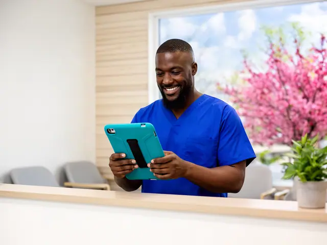 Dental practice office manager in blue scrubs smiling at a tablet behind the front desk